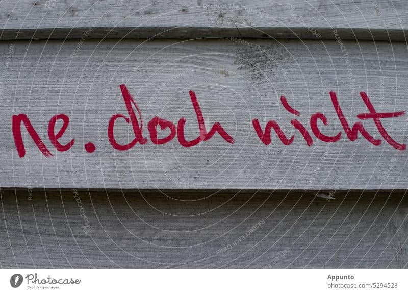 The saying "ne, doch nicht" is painted with red paint on a gray board wall surely not yet ne.yet not Red Colour Gray boards Wall (building) motto phrase writing