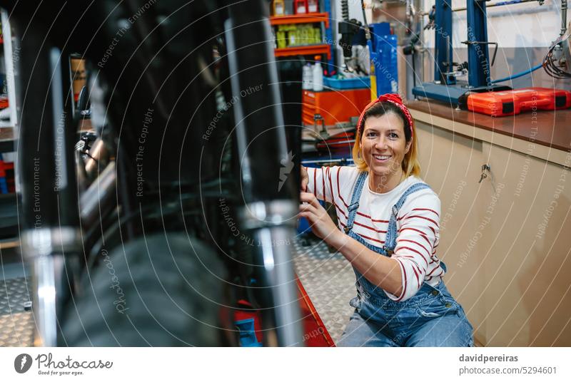 Portrait of mechanic woman repairing motorcycle on factory portrait worker female motorbike freckles looking at camera working happy smile garage review