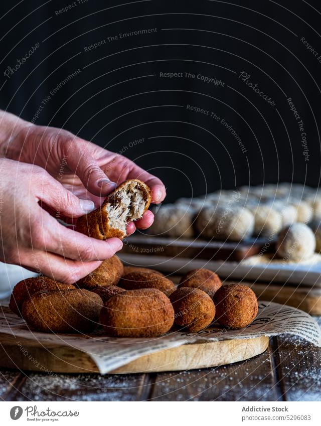 Crop person hands splitting croquette pork cheek show piece crispy portion board bread crumb snack yummy homemade fast food dish culinary kitchen roll meat