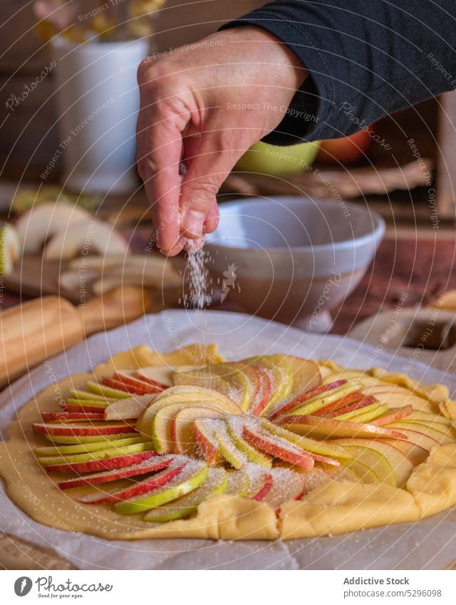 Crop cook sprinkling sugar on apple pie person hand sprinkle galette homemade shortcrust prepare dough unbaked ingredient yummy product recipe process delicious