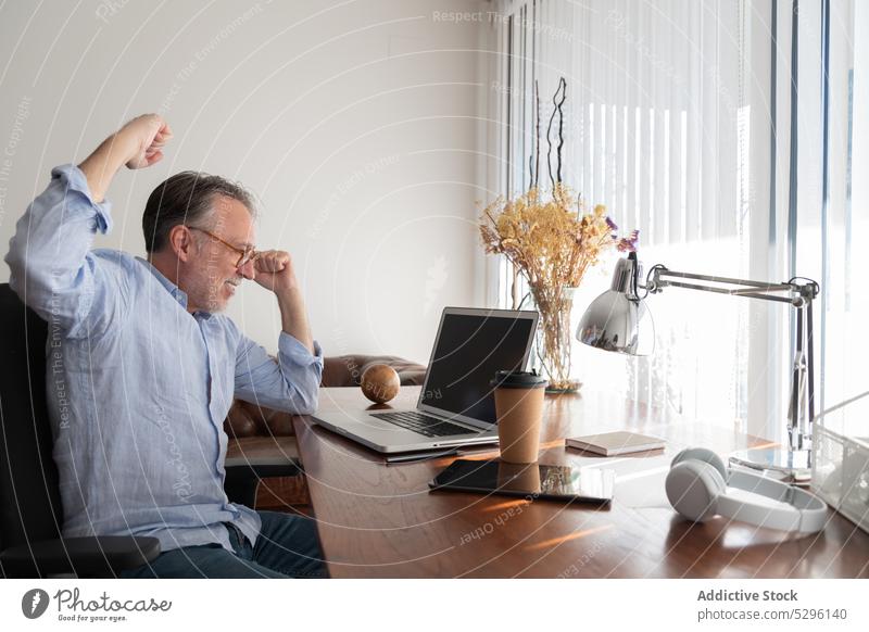 Man making triumph gesture while using netbook man freelance laptop celebrate success achieve clench fist victory empty screen excited home work gadget