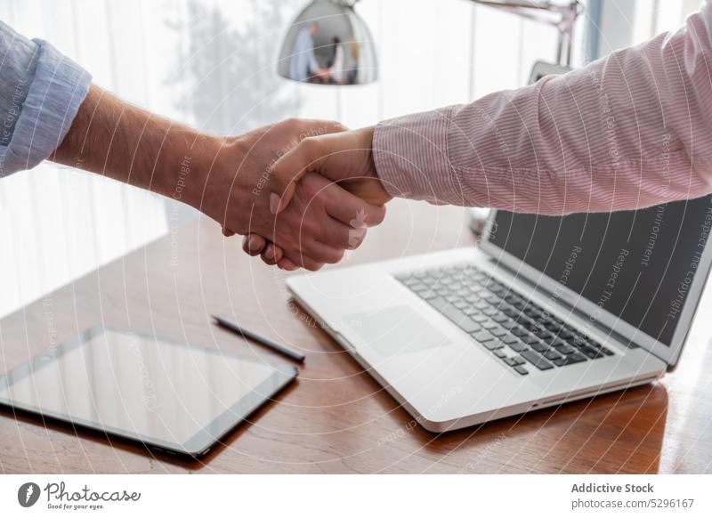 Crop coworkers shaking hands at work handshake deal partner freelance success business collaborate contract laptop tablet office colleague workplace project