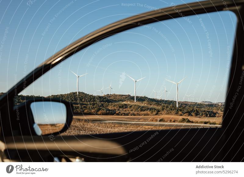 Countryside field with wind turbines car window vehicle nature countryside alternative energy cloudless sky blue sky sustainable ecosystem production windmill
