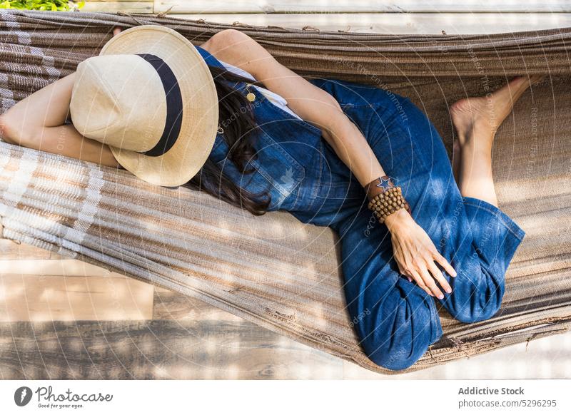 Woman in sunhat resting in hammock woman relax lying summer vacation tranquil carefree leisure lifestyle female holiday trendy outfit daytime young casual