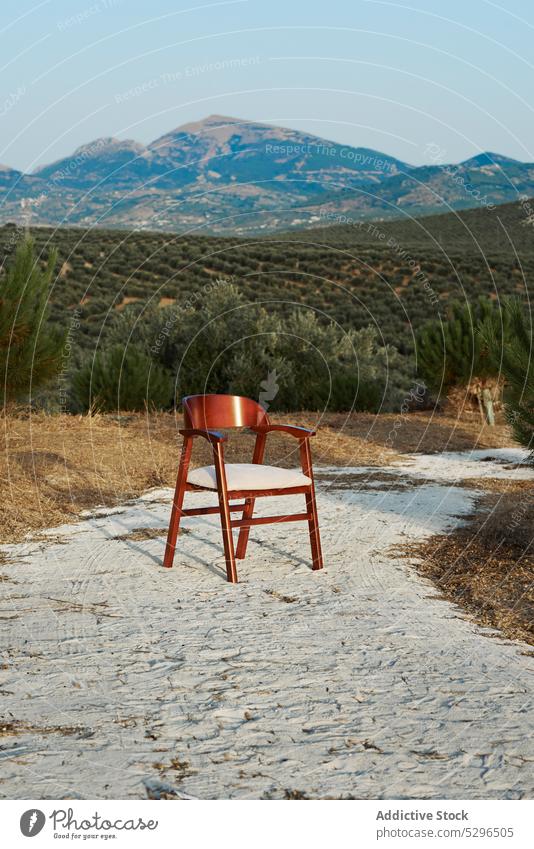 Wooden chair on sandy road nature wooden mountain forest environment pillow cloudless blue sky landscape daytime ground tree countryside hill sunlight peaceful