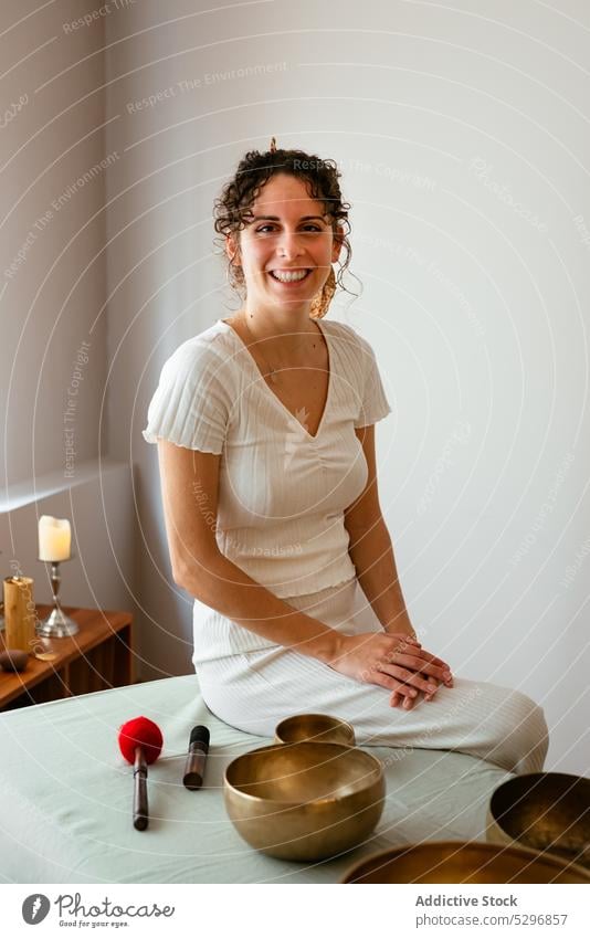 Cheerful woman with Tibetan singing bowl looking at camera in spa center portrait sound massage tibetan singing bowl positive therapist therapy relax music