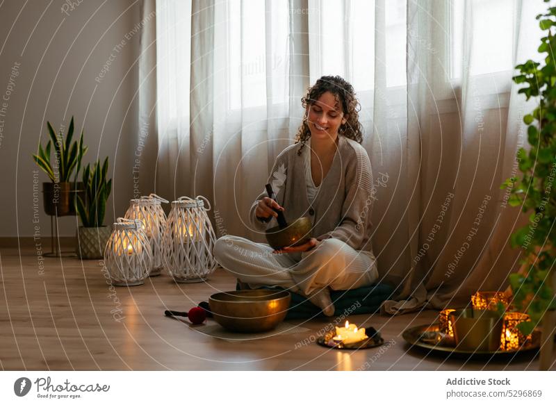 Happy young woman playing singing bowl during meditation meditate smile recreation aromatherapy positive sound spirit yoga relax music tibetan female brunette