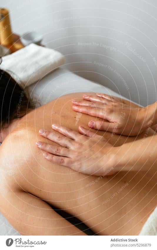 Crop therapist massaging back of female client in spa salon women massage therapy rehabilitation procedure recovery masseuse heal lying patient clinic treat