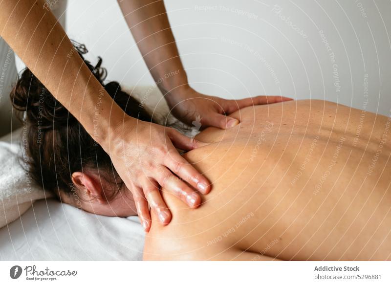 Crop therapist massaging back of female client in spa salon women massage therapy rehabilitation procedure recovery masseuse heal lying patient clinic treat