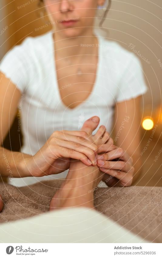 Crop masseuse massaging feet of client in spa salon women massage therapy treat body care lying relax wellness session oil procedure harmony tranquil