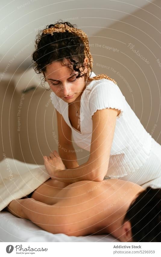 Masseuse massaging back of client at spa man masseur massage therapy therapist procedure elbow relax treat care wellness patient woman healthy lying