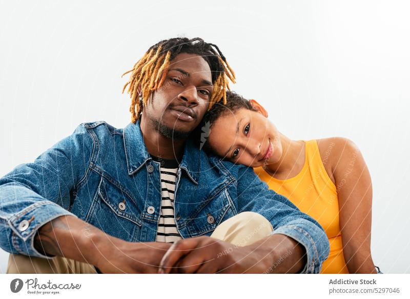 African American couple sitting close to each other in white studio relationship boyfriend girlfriend affection fondness together partner love bonding