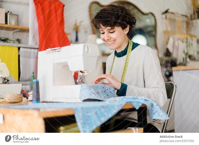 Focused tailor sewing on machine in atelier woman seamstress dressmaker tape designer workshop measure sewing machine pattern female professional workplace