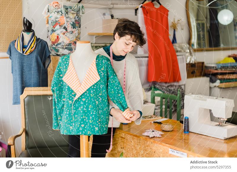 Focused dressmaker checking mannequin in atelier woman tape studio workshop tailor measure designer cloth female creative concentrate seamstress professional