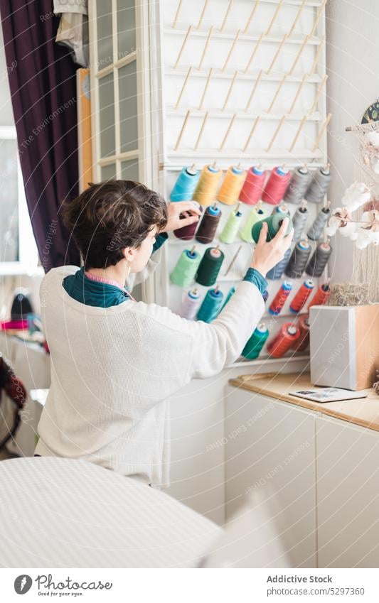 Unrecognizable designer choosing thread for sewing person seamstress choose tailor workshop dressmaker project occupation creative job studio material atelier