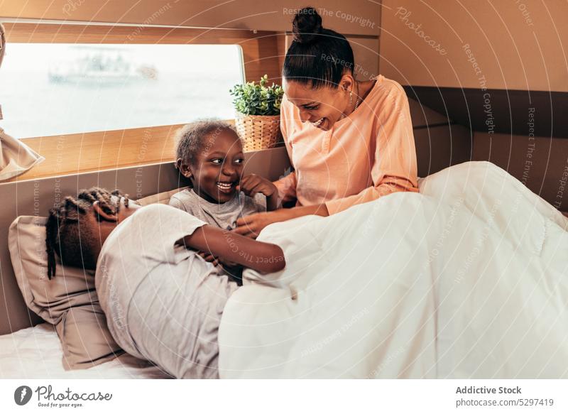 Happy black mother and children having fun in bed play smile rest positive weekend together happy ethnic african american parent sibling daughter son cheerful