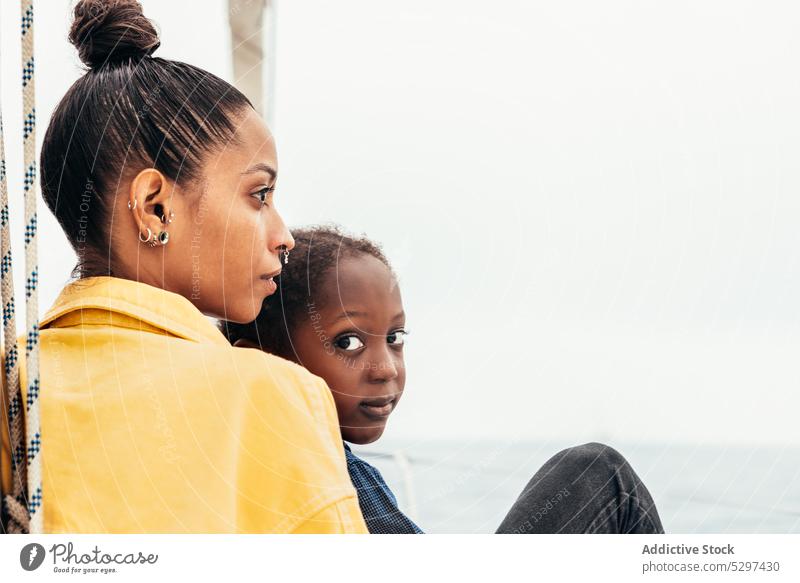 Pensive black woman embracing little son in yatch mother yacht thoughtful together weekend hug boy child casual sea holding summer parent kid affection adorable