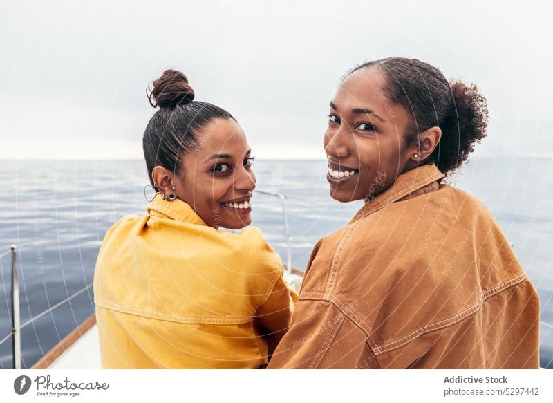 Cheerful black women looking at camera against sea yacht smile beach summer rest friend relax happy together ethnic girlfriend african american weekend ocean