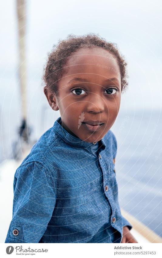 Cheerful black boy smiling and looking at camera on yacht smile positive sea summer childhood water happy casual kid african american cheerful joy rest carefree