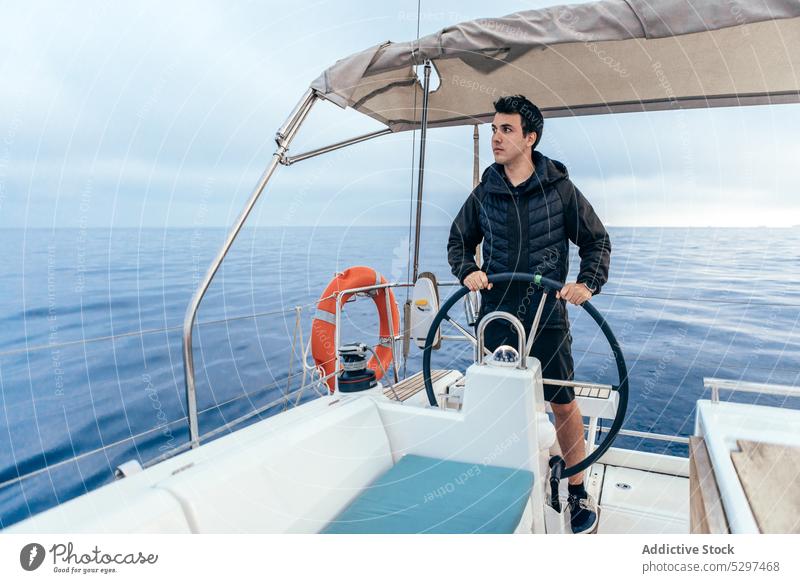 Confident man standing at steering wheel of yacht sea water boat float vessel sailboat travel trip transport male cruise young journey adventure ship summer