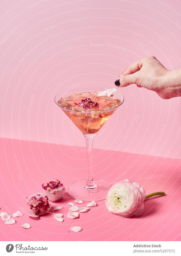 Crop person decorating mocktail with petal pink flower rose sweet glass decorate floral delicious fresh bright drink event tasty decoration blossom beverage