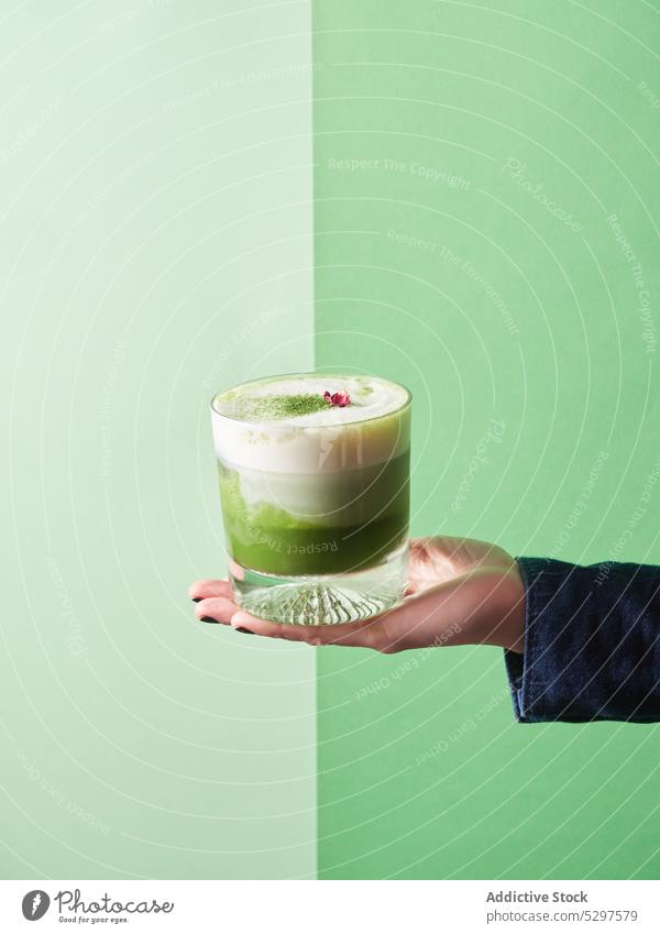 Crop person with glass of matcha latte drink milk beverage refreshment whipped delicious tasty dairy sweet natural tea froth aroma demonstrate yummy flavor