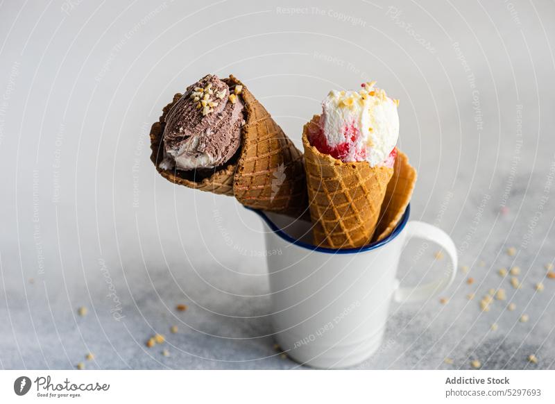 White cup with ice cream cones waffle chocolate cherry cold concrete delicacy dessert food gourmet homemade meal mug nut scoop spoon stripped sweet snack table