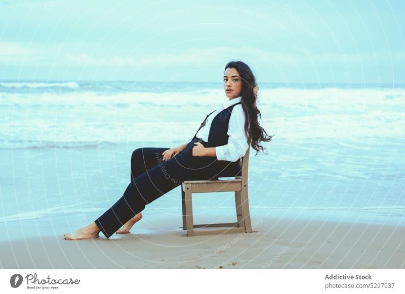 Calm woman sitting on chair near sea beach seashore sand seaside relax rest calm coast young ocean female peaceful style water resort tranquil serene harmony