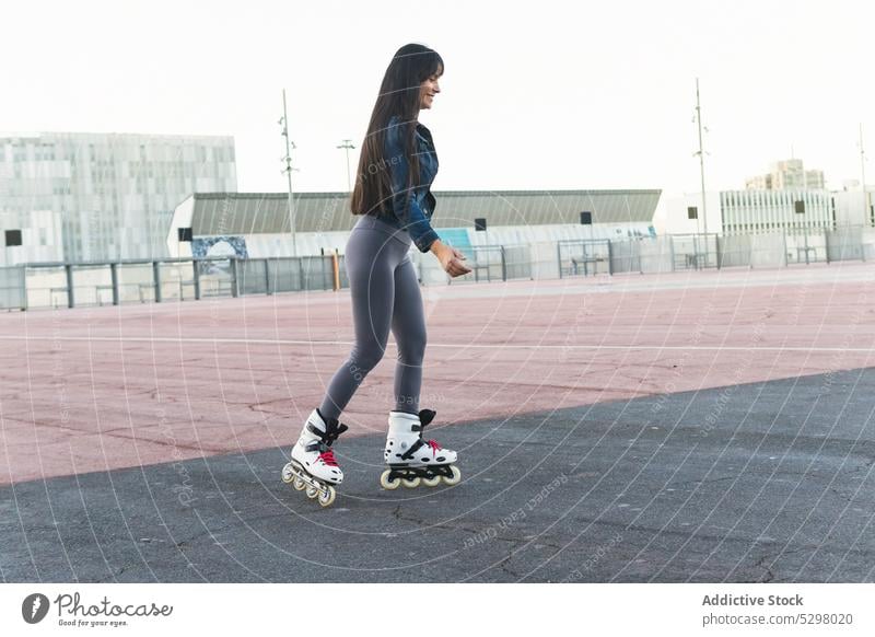 Smiling woman riding roller skates on street ride summer playground activity enjoy sport happy fun female young casual balance hobby cheerful active urban