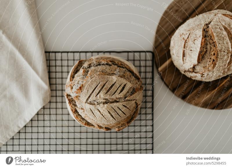 Home made sourdough bread. Resting on cooling rack and wooden board. On the left side there is a linen napkin. Minimalism in a horizontal flat lay image. loaf