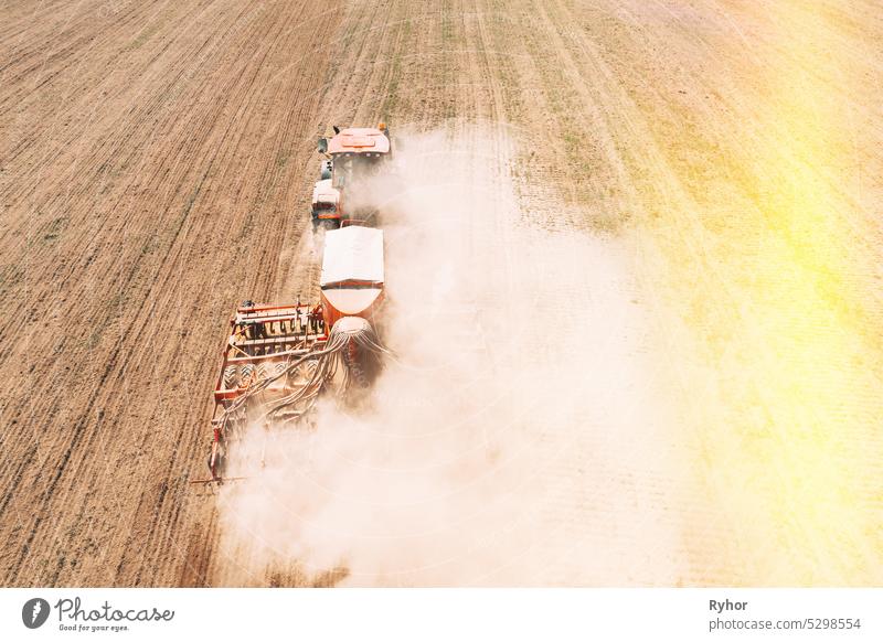 Elevated View Tractor With Seed Drill Machine Sowing Seeds For Crops In Spring Season. Beginning Of Agricultural Spring Season. Countryside Rural Field Landscape. Sunlight sunbeam sunshine