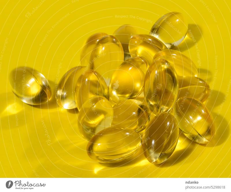 Yellow capsules with fish oil on a yellow background, close up omega omega 3 pharmaceutical pharmacy pill shadow soft studio supplement tablet translucent