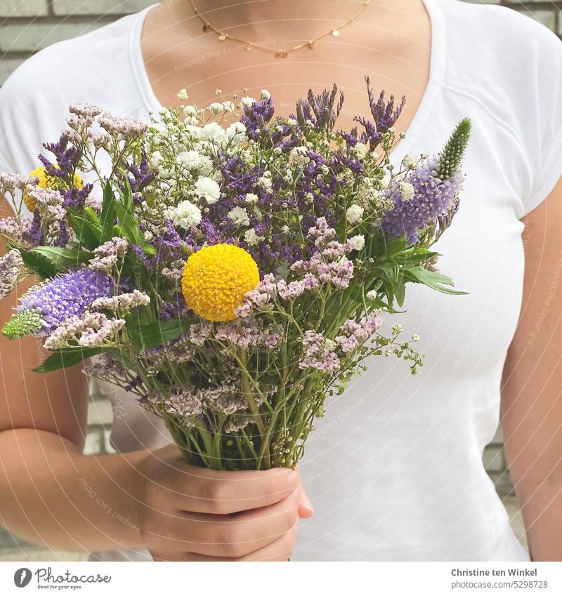 A young woman holds a colorful bouquet of flowers in her hand Bouquet Gift Mother's Day Valentine's Day Hand Birthday Love cut flowers Joy pretty pose