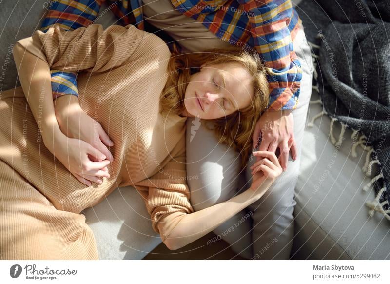 Young beautiful pregnant woman is lying on her husband's lap. Happy young couple relaxing on the couch at home. sleep nap rest baby people family love girl
