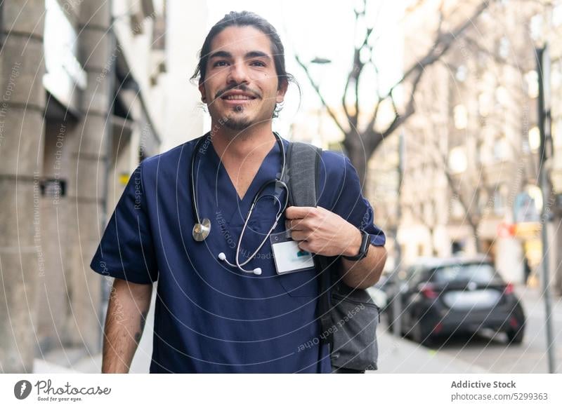 Cheerful ethnic doctor with backpack on street man city stethoscope smile positive medical clinic health care male uniform happy cheerful medicine confident
