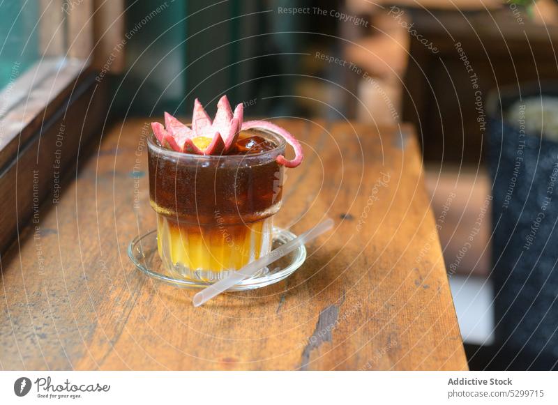Glass of cold brew coffee with flower on top beverage glass drink cafe juice refreshment straw cocktail table vietnamese orange cup wooden delicious tasty