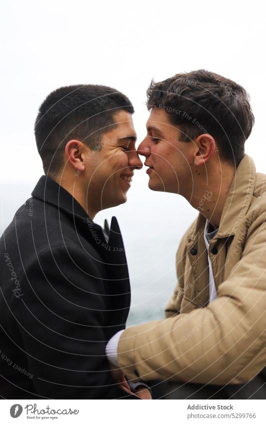 Happy gay couple kissing on street nose love homosexual boyfriend relationship lgbt same sex smile happy young together outerwear romantic amour affection