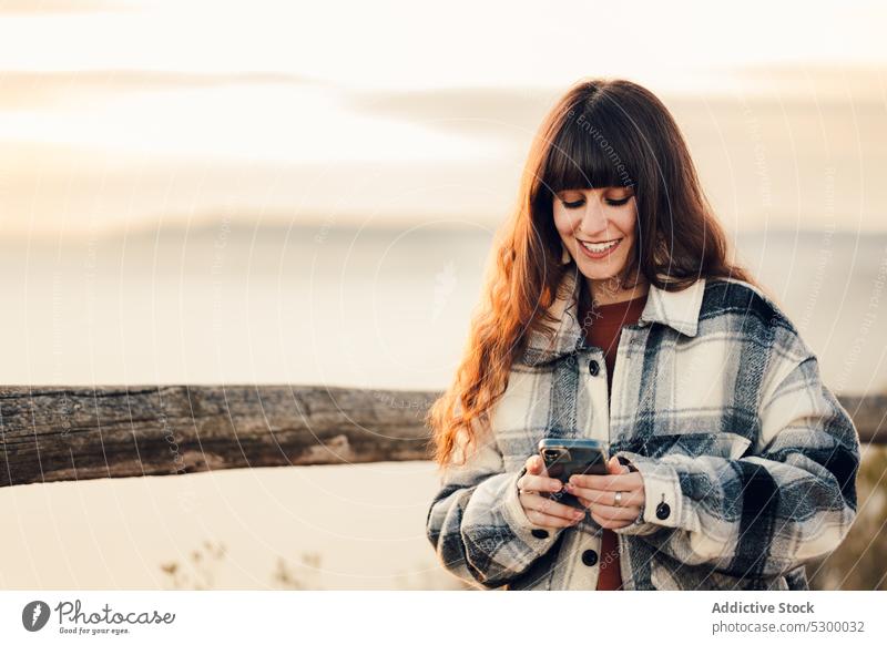 Positive woman browsing smartphone during trip forest using smile cheerful message nature happy weekend mobile female young almatret catalonia spain