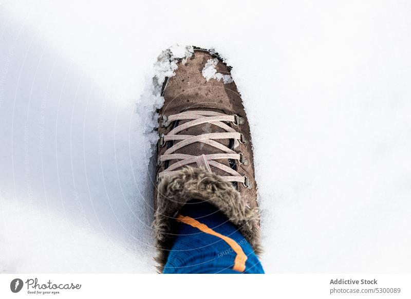 Anonymous person in boots on snow winter cold ground season frost weather footwear nature frozen wintertime stand cool environment warm clothes outerwear shoe