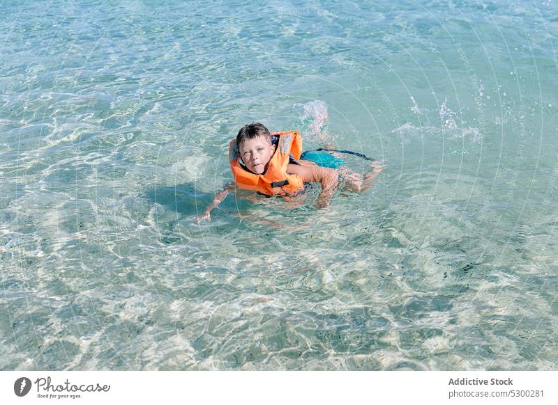 Content kid swimming in sea water boy summer clean holiday child adorable recreation ocean resort cute relax childhood safety from above activity wet nature