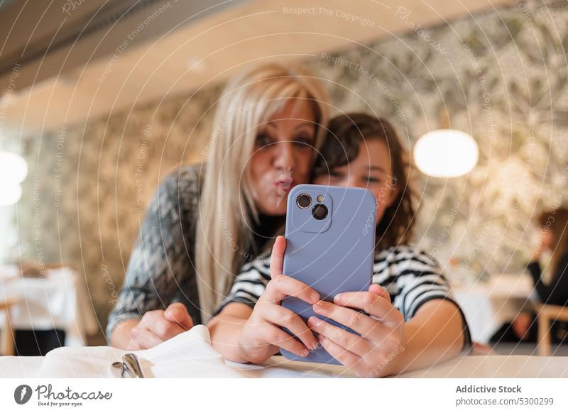 Positive woman and girl taking selfie on smartphone grandmother granddaughter restaurant together happy smile cheerful memory gadget take photo mobile cafe