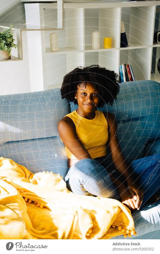 Calm black woman resting on sofa content relax enjoy home smile comfort afro couch african american woman casual curly hair young female hairstyle chill