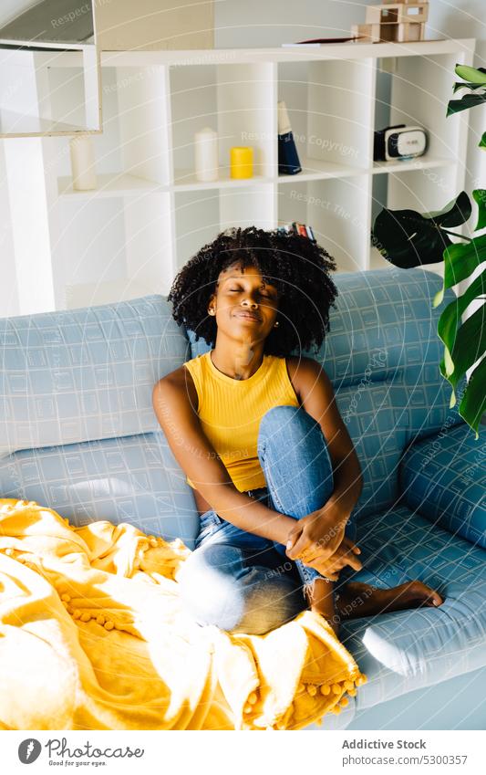 Calm black woman resting on sofa content relax enjoy home smile eyes closed comfort afro couch african american woman casual curly hair young female hairstyle