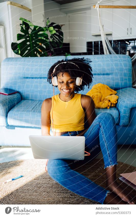 Happy black woman working on laptop freelance smile headphones happy glad delight browsing typing using home african american female young casual remote gadget