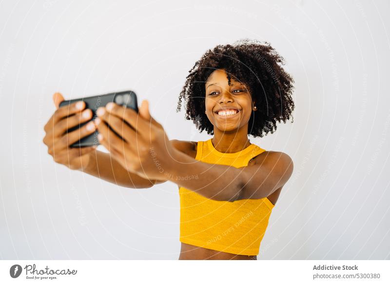 Joyful black woman taking selfie smartphone self portrait using afro grimace cheerful happy african american ethnic hairstyle crop top female gesture young