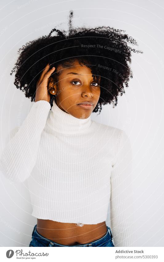 Slim black woman in white studio touch hair model style appearance portrait hairstyle casual afro trendy african american apparel fashion curly hair young