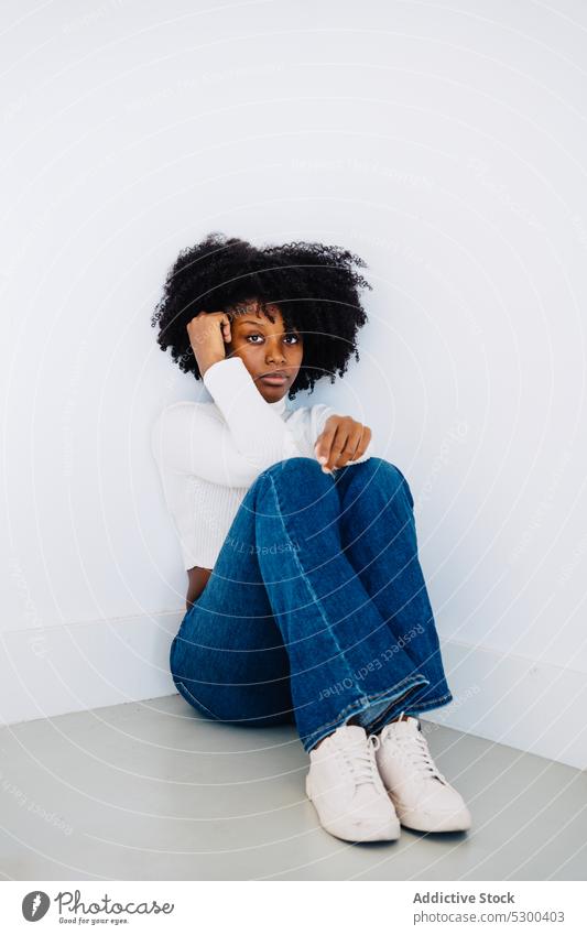 Calm black woman sitting on floor thoughtful calm pensive serious appearance curly hair hairstyle tranquil female young african american casual afro trendy rest