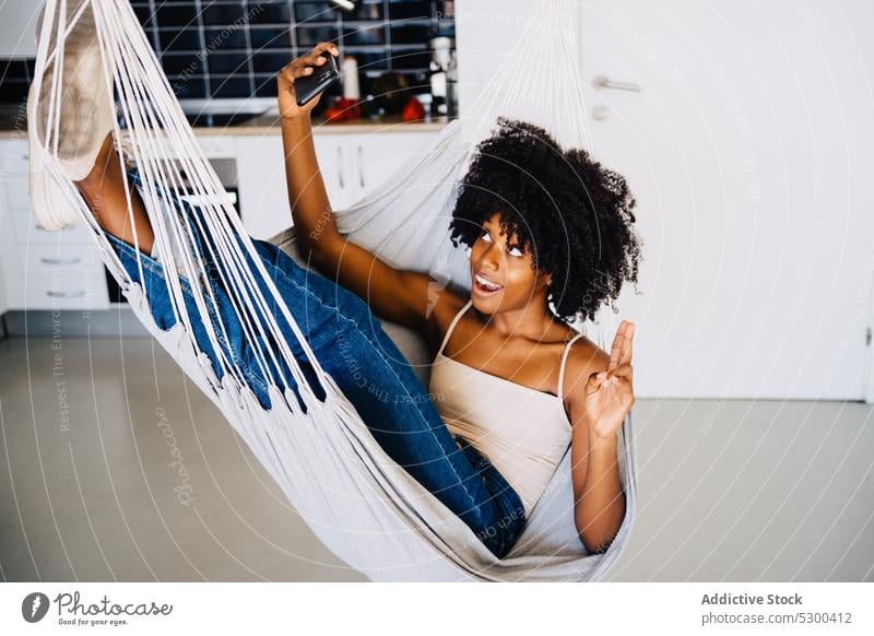Happy black woman taking selfie on hammock smartphone v sign smile gesture cheerful peace using african american young female happy positive casual rest