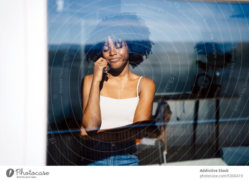 Trendy black woman with eyes closed near window calm afro pensive smile reflection hairstyle home female glad african american woman young delight thoughtful