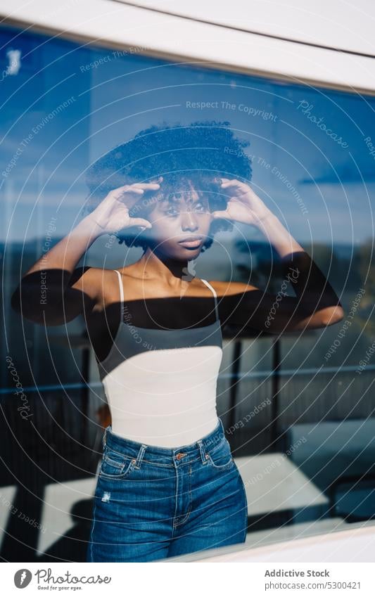 Trendy black woman looking at window calm serious touch hair afro pensive reflection hairstyle home female african american woman young thoughtful curly hair